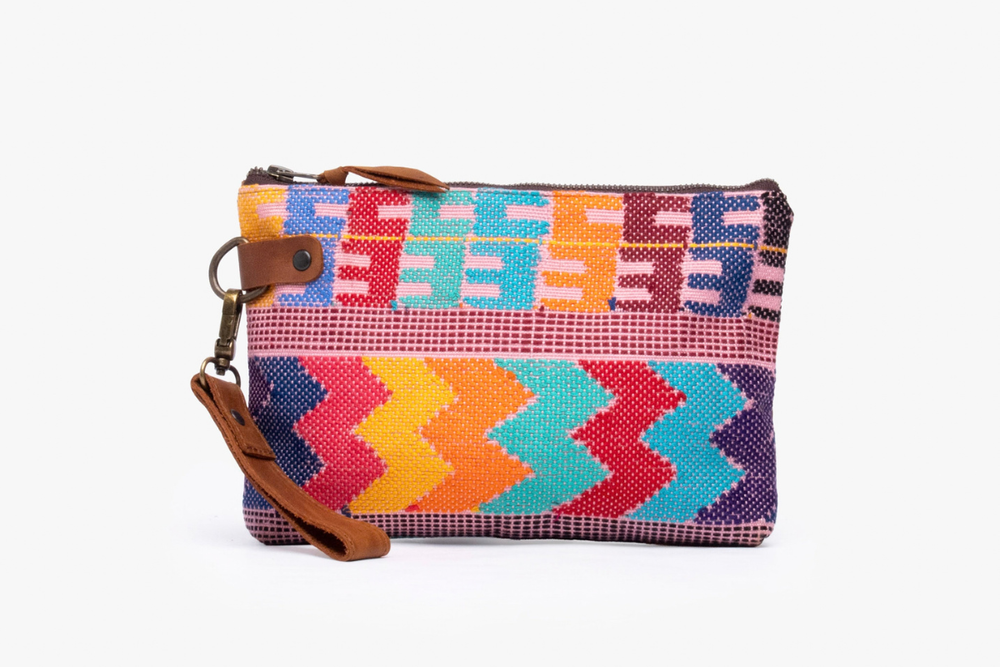 A small woven clutch pouch with a colorful geometric pattern, brown leather strap, and metal ring clasp, shown on a plain white background.