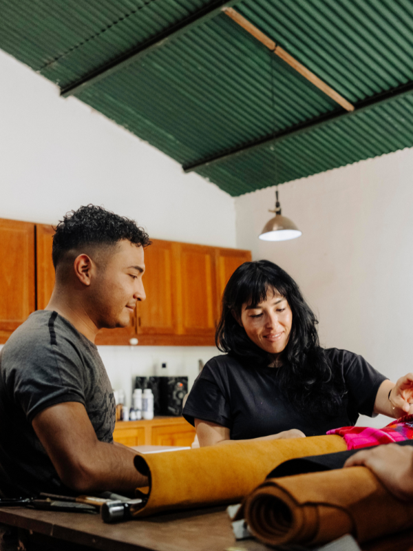 One man and one woman looking over leather selection on table